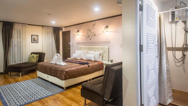 Une chambre d’hôtel comprenant un lit, une chaise, une petite table et un espace douche.