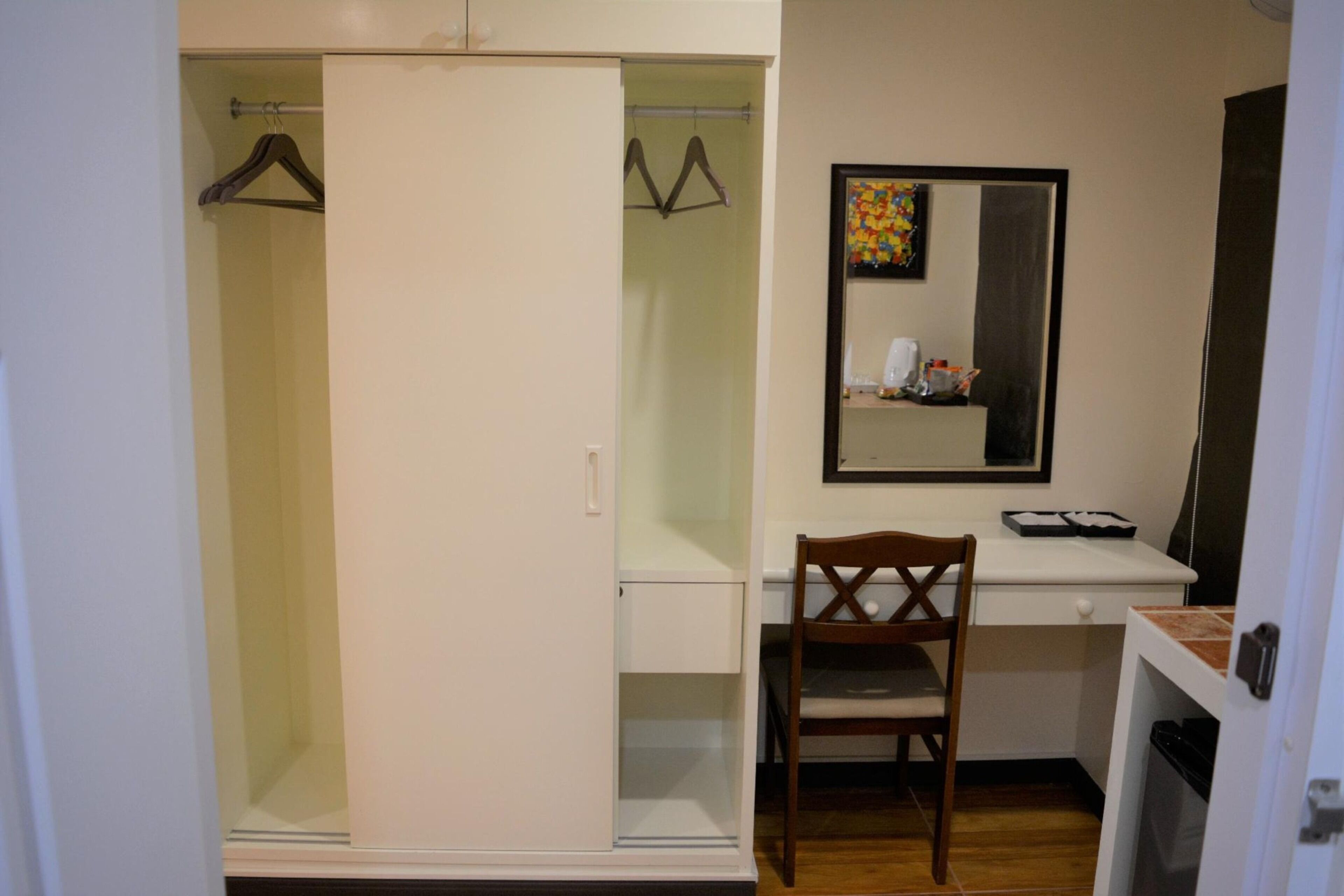Quarto compacto com guarda-roupa, escrivaninha, cadeira e espelho.