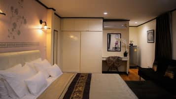 A hotel room with a bed, a desk, a chair, and a sofa.