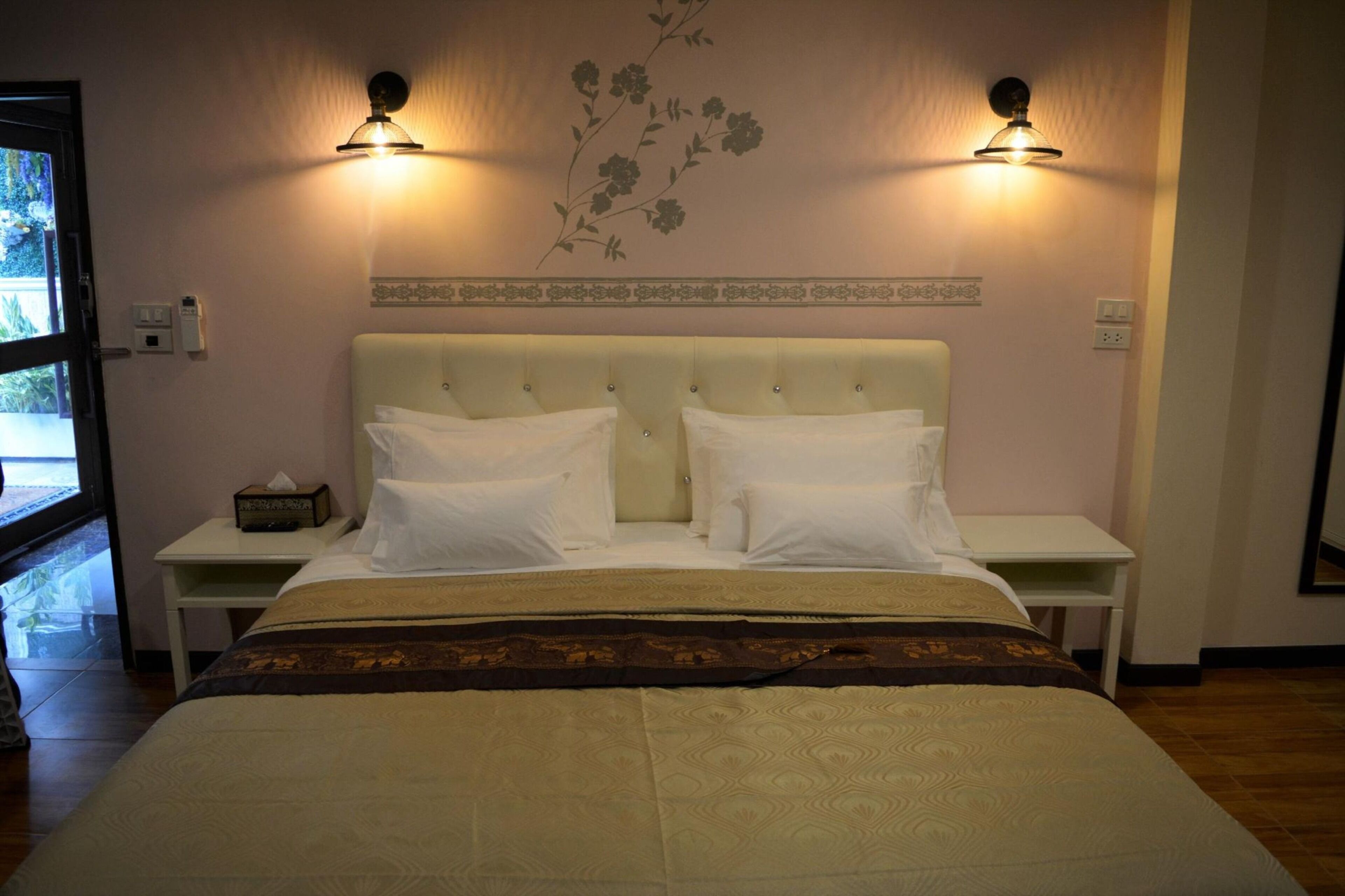 A hotel room with a large bed, two bedside tables, and wall-mounted lamps.