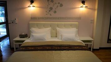 A hotel room with a large bed, two bedside tables, and wall-mounted lamps.