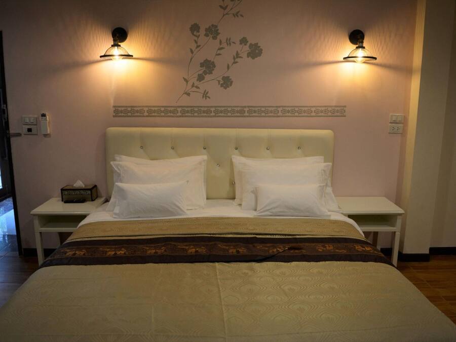 A hotel room with a large bed, two bedside tables, and wall-mounted lamps.