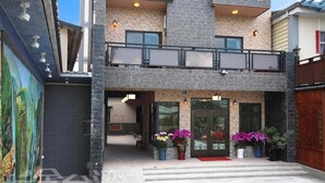 Un edificio moderno de dos pisos con fachada de piedra, ventanas amplias y un balcón.
