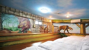 Una habitación con un mural que muestra un dinosaurio y un caballo, una escalera y una cama.