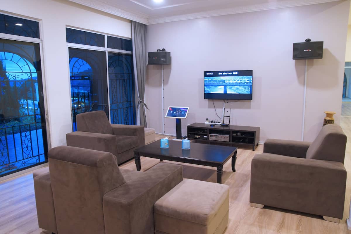 A modern living room with a flat-screen TV, two sofas, a coffee table, and a large window with a view of a building.