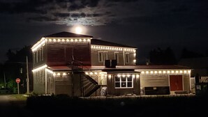 Une maison à deux étages avec un garage, illuminée de guirlandes lumineuses, sous une pleine lune.