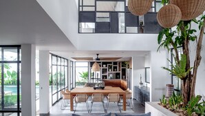 Un intérieur moderne comprenant un coin repas, une cuisine et de grandes fenêtres donnant sur une piscine.