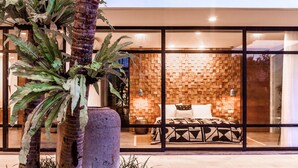 Un intérieur moderne avec un grand lit, un mur en bois et une porte en verre donnant sur un balcon.