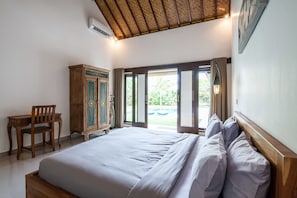 A bedroom with a large bed, a wooden desk, and a wardrobe. - Casaluna Villa (Seminyak)