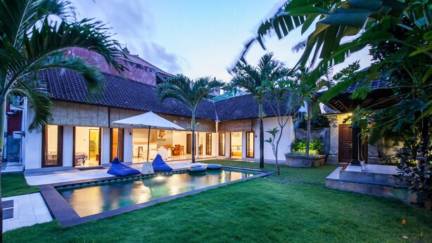 Uma casa moderna com piscina, área de estar externa e um jardim bem cuidado.