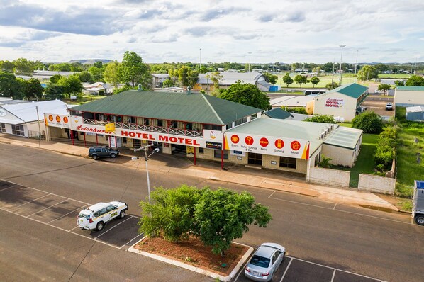 A hotel with a prominent sign, a parking lot, and a green field in the background. - Leichhardt Hotel Motel (Cloncurry)