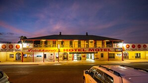 A hotel with a prominent sign reading "HOTEL MOTEL" and various amenities listed such as Pool Table, Jukebox, DJ Music, and a drive-thru. - Leichhardt Hotel Motel (Cloncurry)
