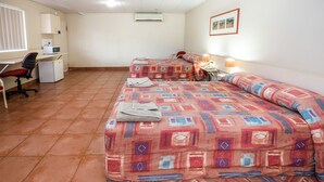 A room with two beds, a desk, a chair, and a small kitchenette. - Leichhardt Hotel Motel (Cloncurry)