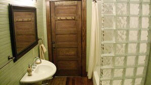Ein Badezimmer mit Holztür, Waschbecken mit Handtuch und Duschvorhang.