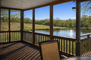 Um espaço coberto ao ar livre com vista para um lago e árvores.