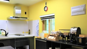 Cocina compacta con estufa a gas, lavamanos, microondas y cafetera.