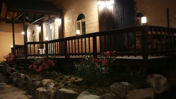 Un edificio de piedra con una terraza de madera y un muro de piedra.