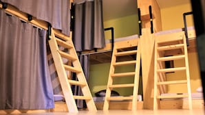 Una cama litera con escaleras de madera y una cortina.