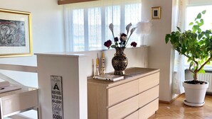A modern kitchen with wooden cabinets, a central island with a vase of flowers, and a potted plant. - A spacious house with amazing view (Grafarvogur)