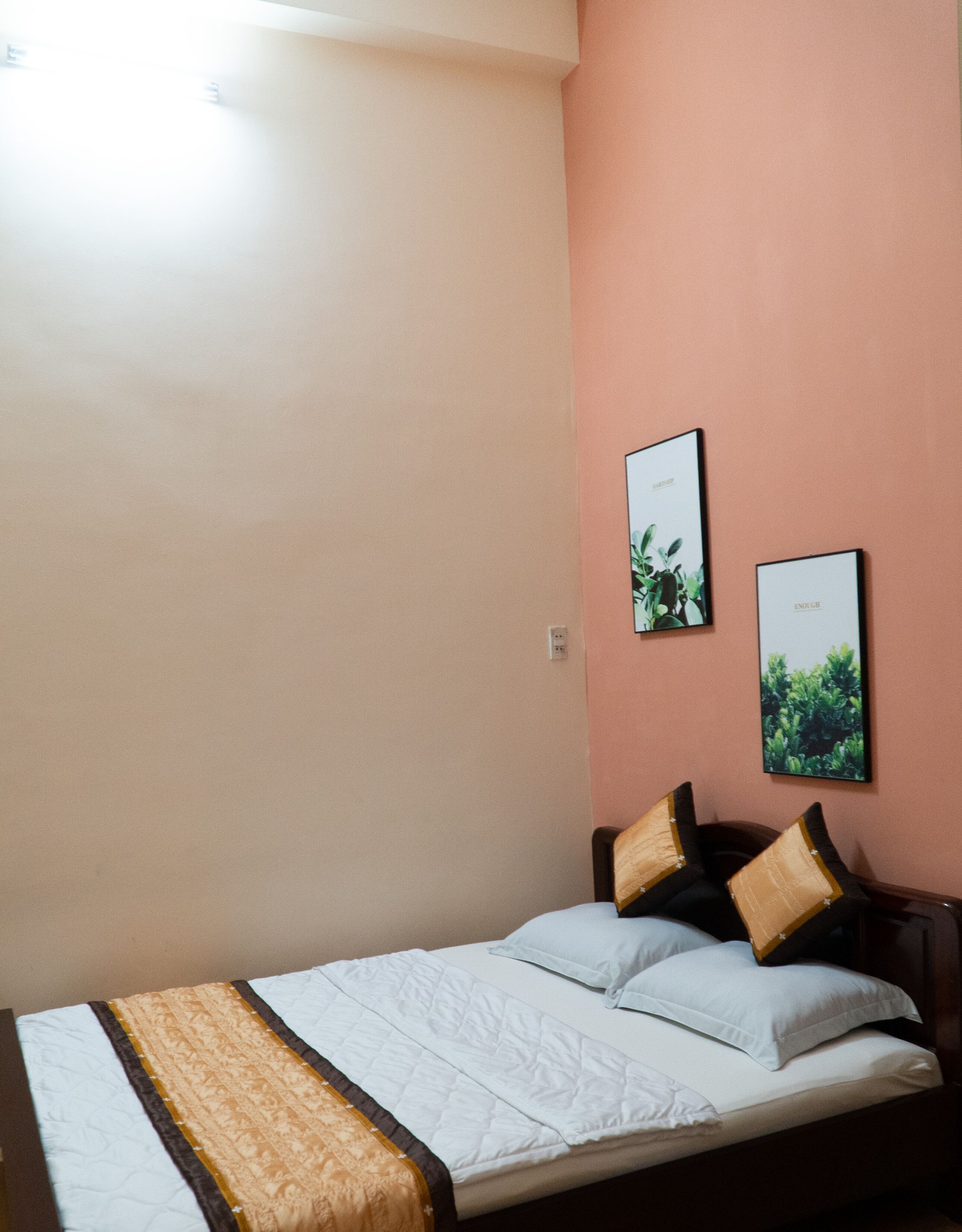 A bedroom with a bed, two framed pictures on the wall, and a bedside table.