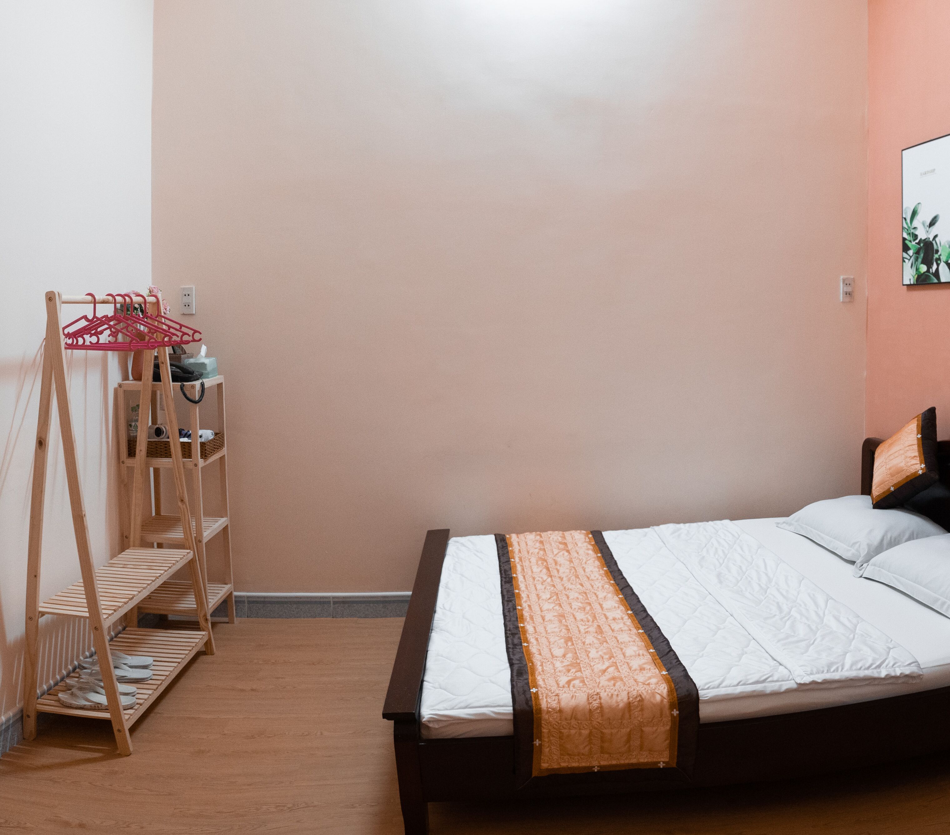 Ein Schlafzimmer mit einem Bett, einer Holzregaleinheit und einem Wandregal.