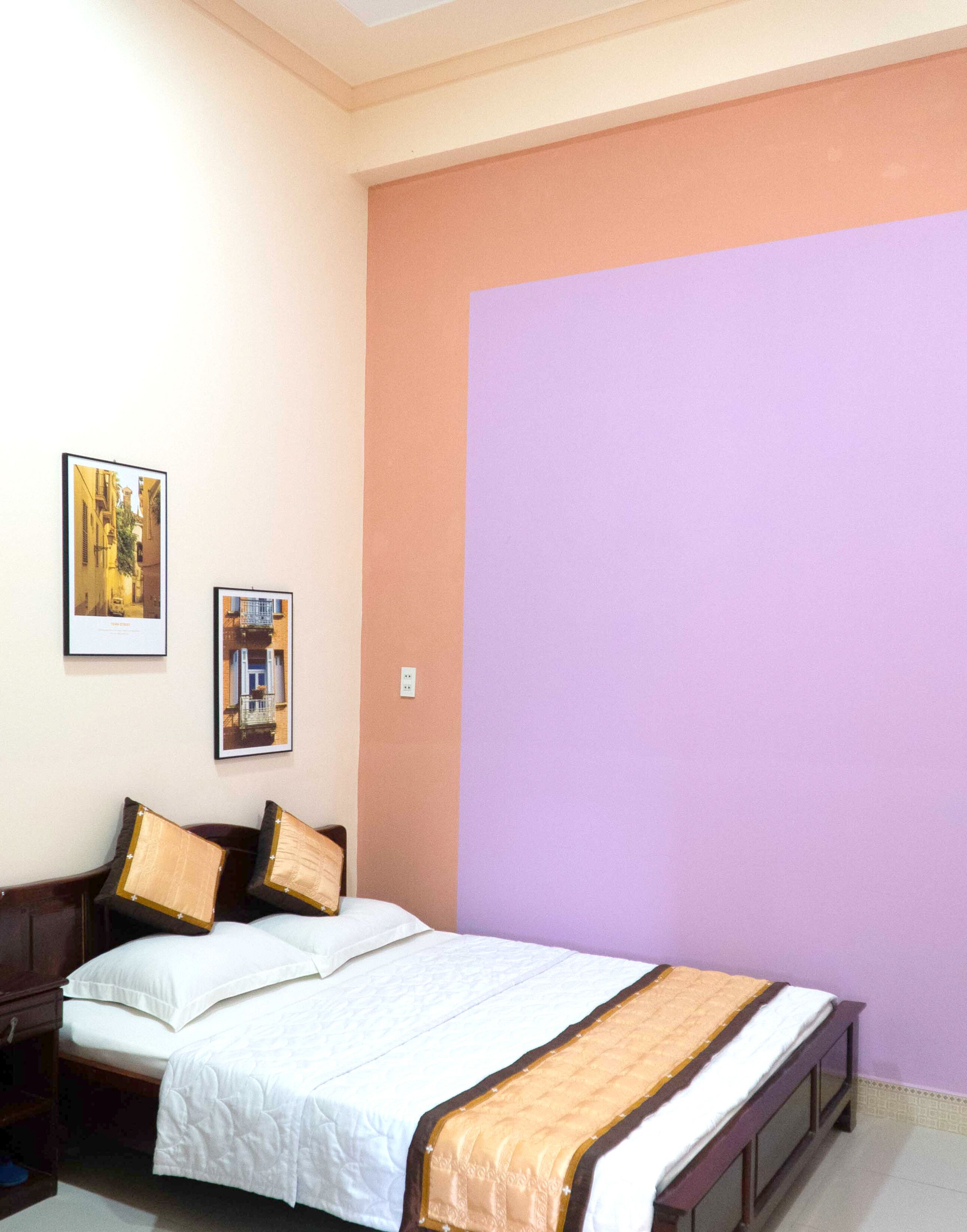 A bedroom with a bed, two pillows, a nightstand, and two framed pictures on the wall.