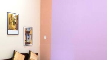 A bedroom with a bed, two pillows, a nightstand, and two framed pictures on the wall.