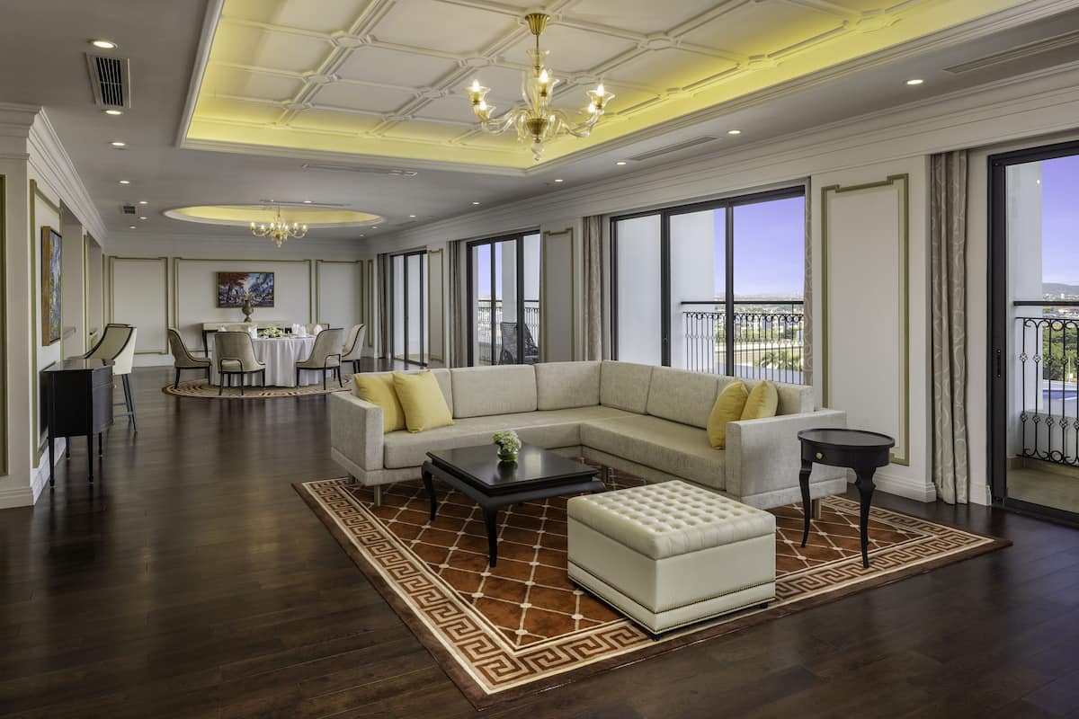 A spacious living room with a large sectional sofa, a coffee table, and a dining area in the background.