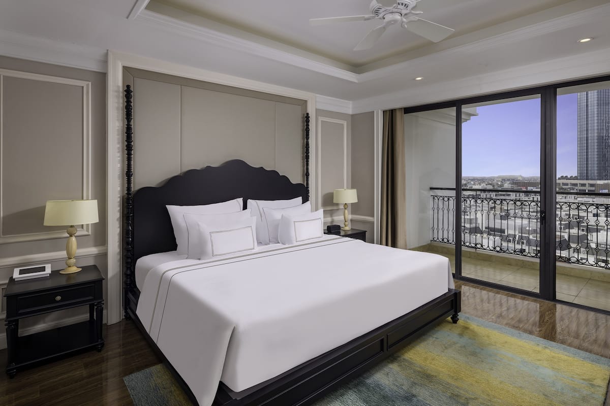 A large bed with white linens, a dark headboard, and two bedside tables with lamps.