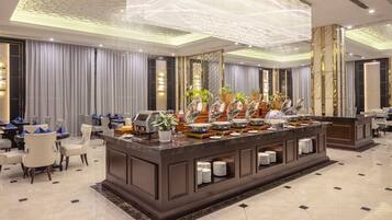 A hotel lobby with a buffet area, seating arrangements, and a decorative ceiling.