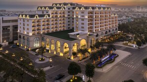 Un grand hôtel à plusieurs étages, de style architectural classique, caractérisé par des fenêtres en arc de cercle et une cour intérieure.