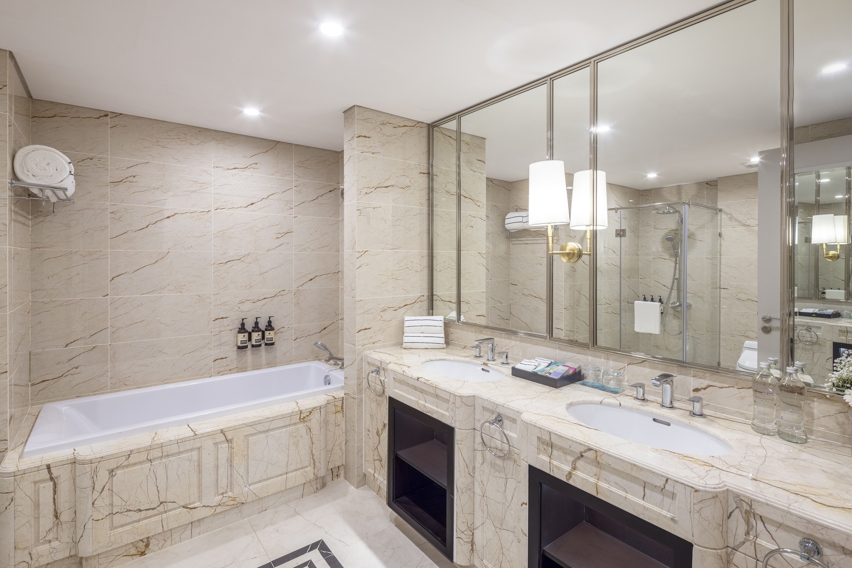 A modern bathroom with a large bathtub, two sinks, and a large mirror.