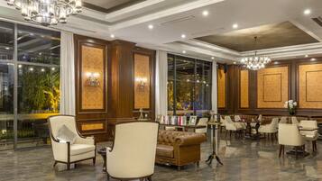 A spacious lobby with a high ceiling, chandeliers, and a seating area with leather sofas and armchairs.