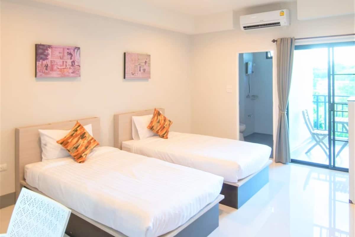 Une chambre d’hôtel avec deux lits, un balcon avec vue et un appareil de climatisation.