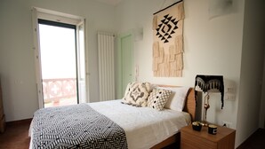 Un dormitorio con una cama, una mesita de noche, un adorno de pared y una puerta a un balcón.