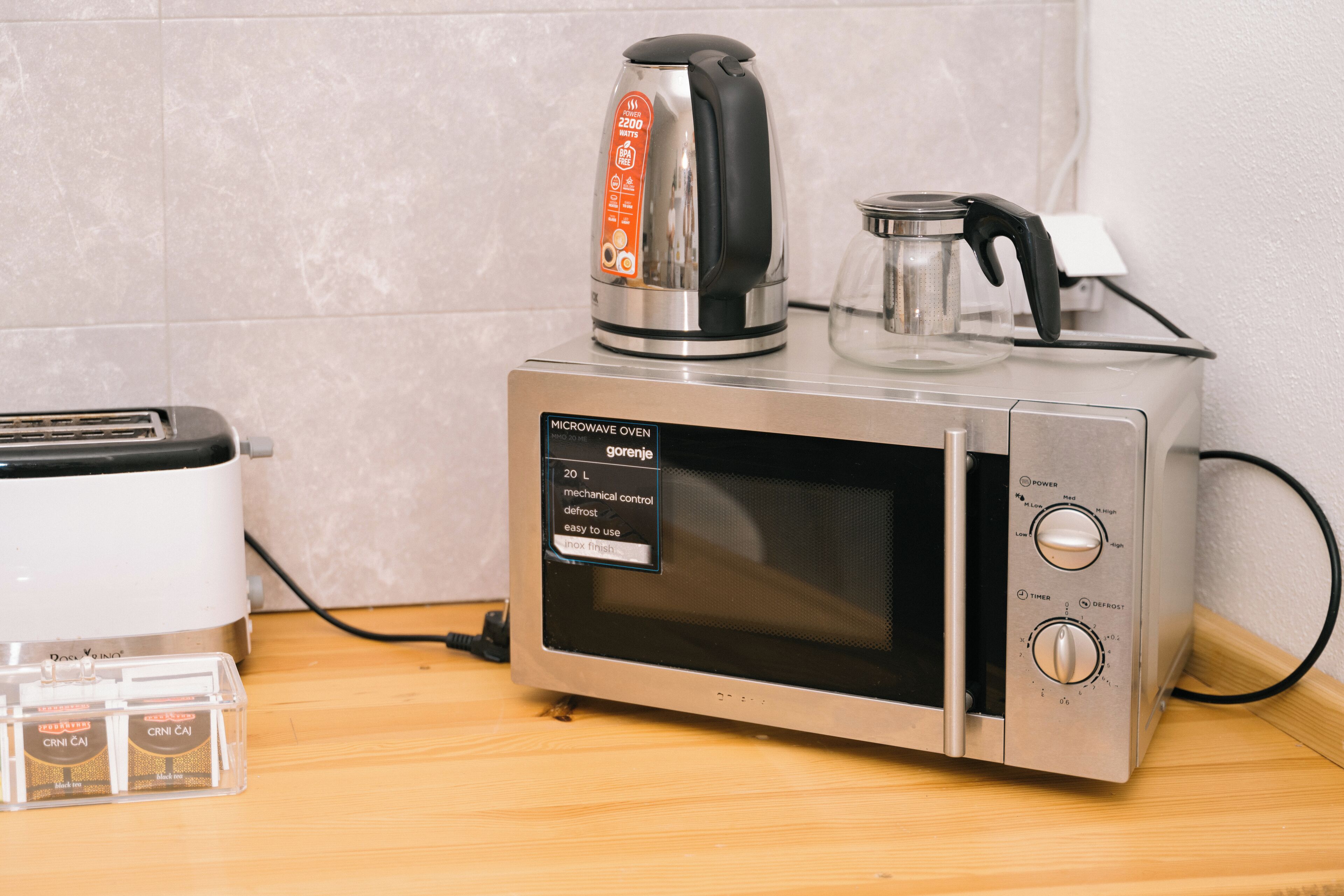 Eine Mikrowelle mit einem Wasserkocher darauf, ein Toaster und eine Packung Snacks.