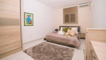 Een slaapkamer met een bed, nachtkastje en een airconditioning.
