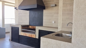 Eine moderne Küche mit eingebautem Backofen, einer großen schwarzen Dunstabzugshaube und einem in die Arbeitsplatte integrierten Spülbecken.