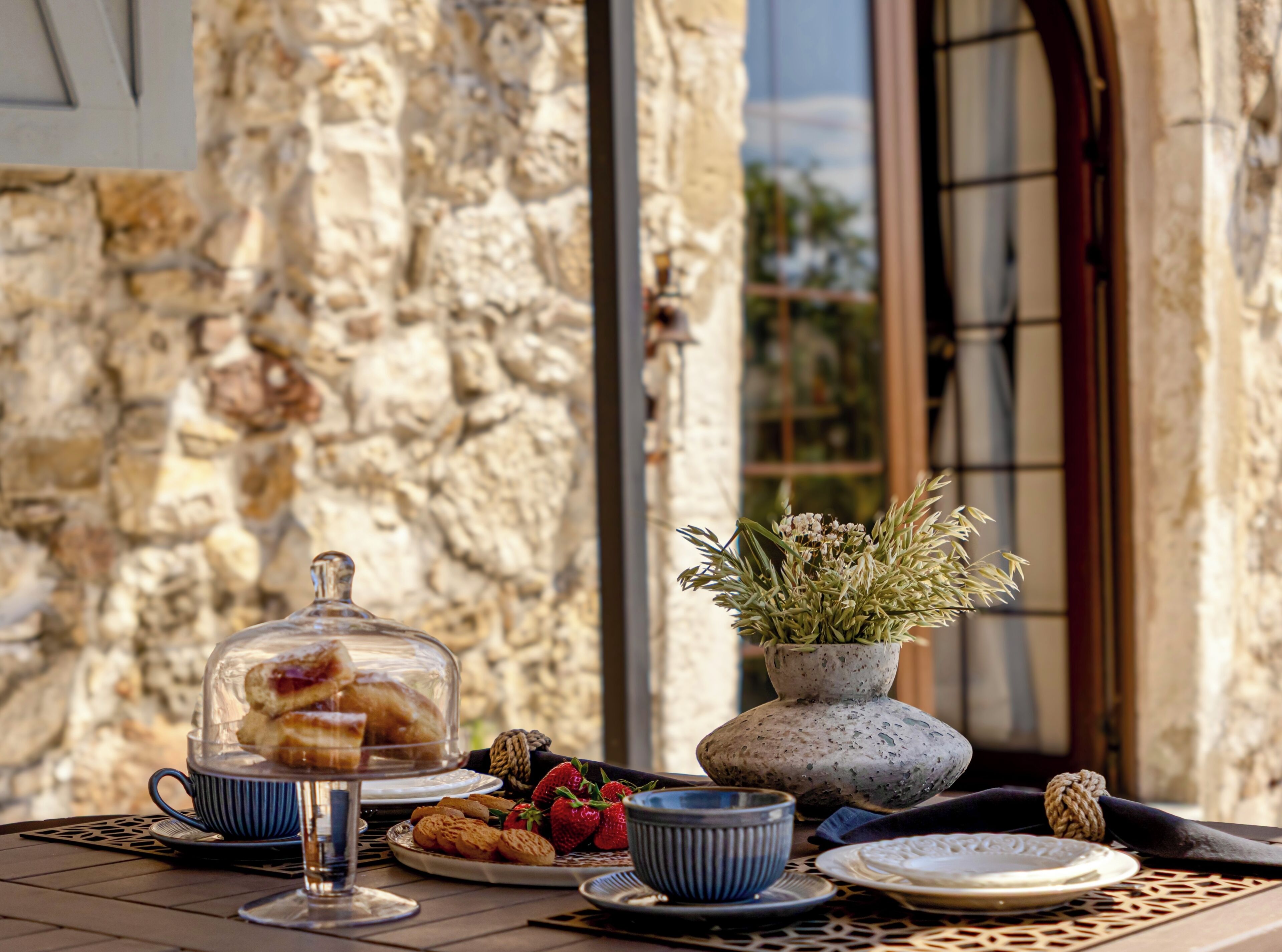 A table set with pastries, a glass of drink, and a potted plant.