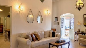 Un soggiorno con divano, tavolino, specchi a parete e un lampadario.