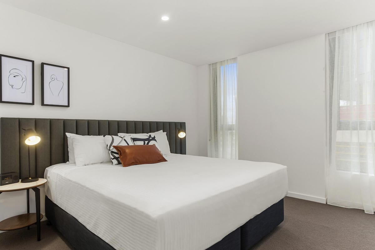 A neatly arranged hotel room with a large bed, bedside tables, and framed artwork on the wall.