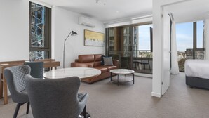 Une chambre d’hôtel moderne dotée d’un grand balcon, d’un canapé, d’une table à manger et d’un lit.