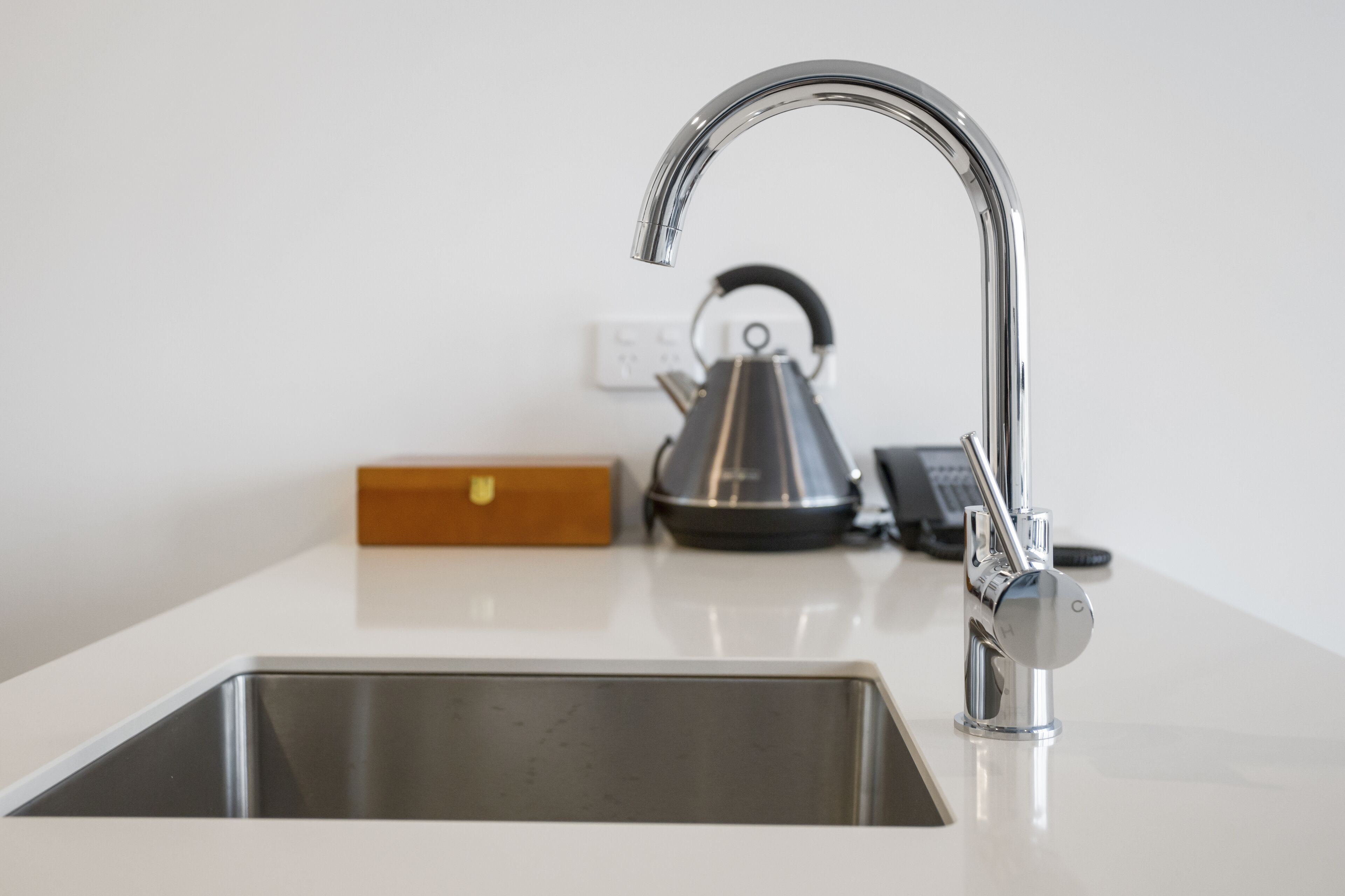 A modern kitchen with a stainless steel sink, a kettle, and a toaster.