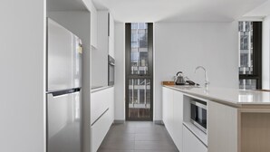 Une cuisine moderne avec des meubles blancs, un réfrigérateur en acier inoxydable, un four à micro-ondes et une fenêtre donnant sur la ville.
