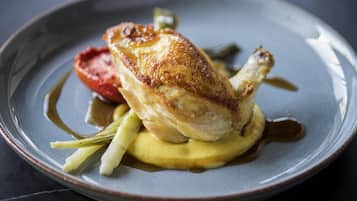 A plate with a roasted chicken, vegetables, and sauce.