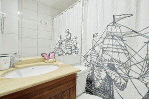 Un baño con un lavamanos blanco, un espejo y una cortina de ducha con un diseño abstracto en blanco y negro.