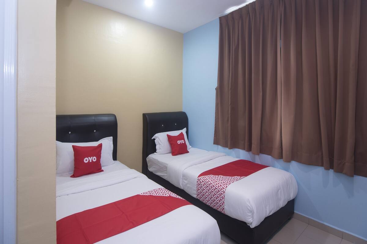 A hotel room with two beds, each with a black headboard and red and white bedding.