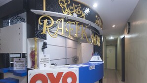 A reception desk with a sign reading "RAFKAR" and "OYO" hotel name, a security camera, a sign indicating break time, and a reception counter. - Hotel O Rafik Ali Motel (Kepala Batas)