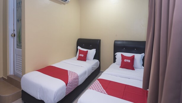A hotel room with two beds, each with a red and white bedspread and matching pillows. An air conditioning unit is mounted on the wall above the beds. - Hotel O Rafik Ali Motel (Kepala Batas)