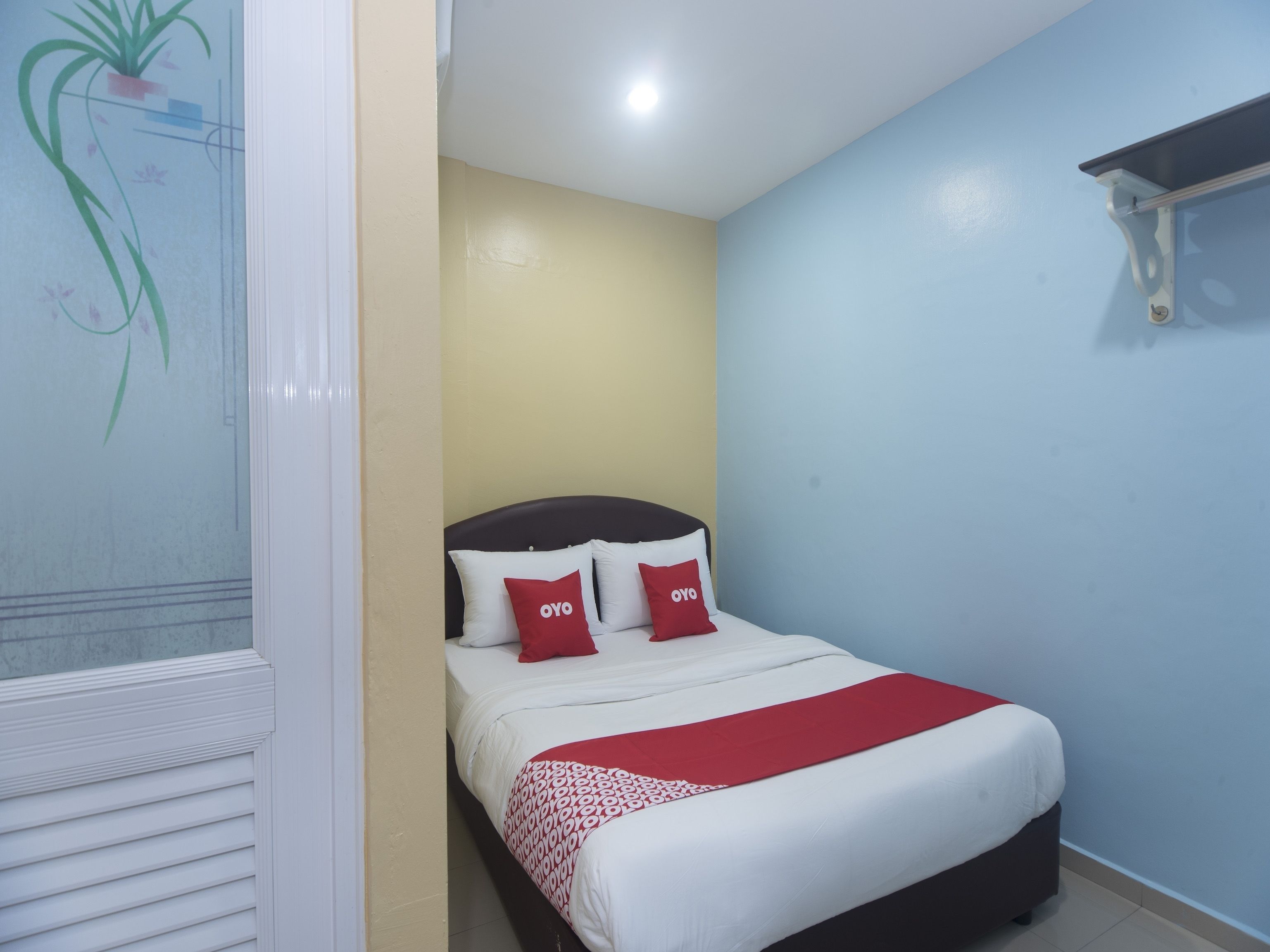 A bedroom with a bed, a red and white bedspread, and two red pillows with "OYO" text.